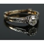 An 18ct gold platinum and diamond ring. A single stone (0.25ct) flanked by diamond set shoulders.