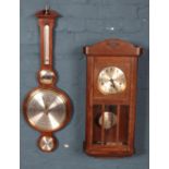 A Howard Miller banjo barometer along with a carved oak wall clock.