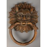 A carved wooden mask formed as a sanctuary door knocker. Signed to the back J. Sarabia. 41cm x 31cm.