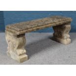 A concrete garden bench raised on two decorative pedestals. Length of top 100cm.