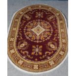 A red ground oval rug with central medallion design. (200cm x 141cm)