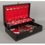 A large black cantilever jewellery box containing a collection of costume jewellery, including