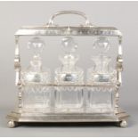 A silver plated three decanter tantalus, with three silver decanter labels. Labels assayed for