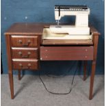 An oak sewing table housing a Singer Futura electric sewing machine.