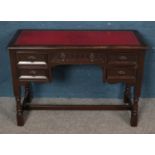 A Priory style carved oak knee hole desk with red leather inset top. (73cm x 107cm)