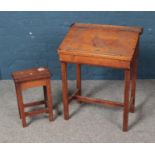 A traditional child's school desk with hinge top along with small stool.