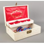 A cream cantilever jewellery box, containing an assortment of costume jewellery, including brooches,