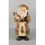 A carved and painted wooden figure of Father Christmas delivering presents. Approx. 47cm tall.