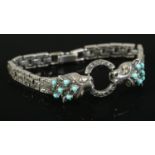 A silver, marcasite and turquoise bracelet, featuring two cats clutching a hoop in their mouth.