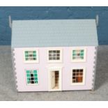 A pink child's dollhouse including accessories such as furniture and dolls. Some damage to