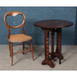 An oak drop leaf table with turned supports together with a bergÃ¨re base balloon back chair.