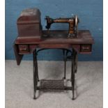 A Wheeler & Wilson treadle sewing machine with various accessories including buttonholer, bobbins