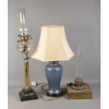 Two brass paraffin lamps and one ceramic modern table lamp.