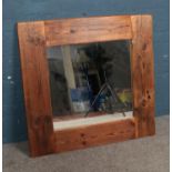 A large wooden framed rustic style wall mirror. Dimensions including frame approx. 96cm x 92cm.