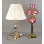 A decorative pink glass paraffin lamp with one other table lamp.