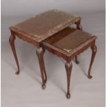 A pair of walnut nesting tables featuring glass tops set on cabriole legs. Largest table approx.
