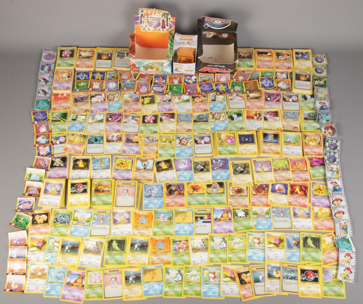 A large quantity of loose PokÃ©mon cards and stickers along with original Team Rocket booster pack