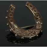 A 9ct gold brooch formed as a horseshoe with floral decoration. 3.56g