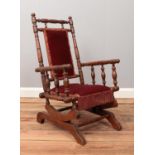 A mahogany child's American rocking chair, with turned bobbin supports, in red fabric upholstery and