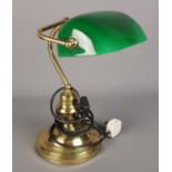 A brass desk lamp with green glass shade.