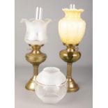 Two brass oil lamps with shades and funnels, along with an additional globular shade.