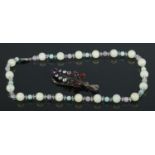 A string of hardstone beads with continental silver clasp, together with a gem set leaf brooch.