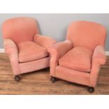 A pair of Howard & Son style red upholstered armchairs raised on turned mahogany supports.