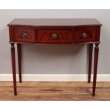 A mahogany three drawer side table with reeded tapering supports.