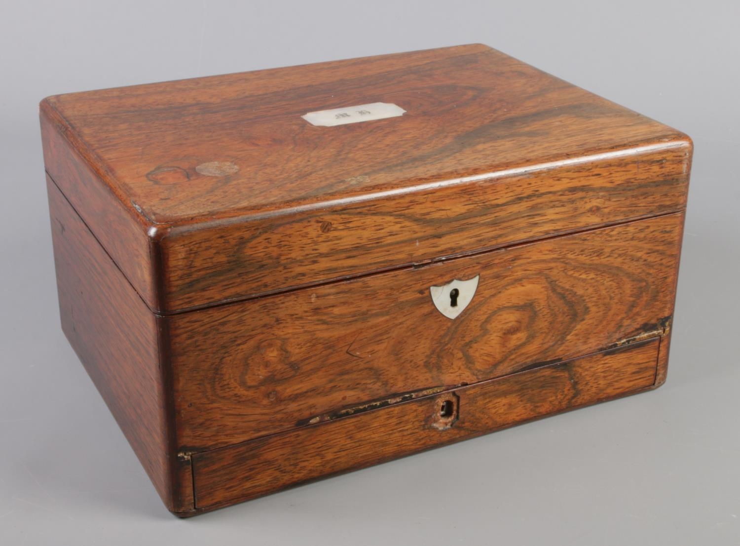 A Victorian rosewood box with mother of pearl inlay and fitted interior.