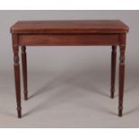 A Georgian mahogany fold over tea table with turned supports.