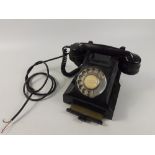 A vintage Bakelite telephone with a rotary dial and a drawer for storing phone numbers etc