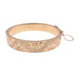 A substantial 9ct hallmarked yellow gold snap-shut bangle with safety chain and floral half band