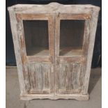 An Indian white wood glazed cabinet with 2 shelves, 2 small drawers and partial glazed doors