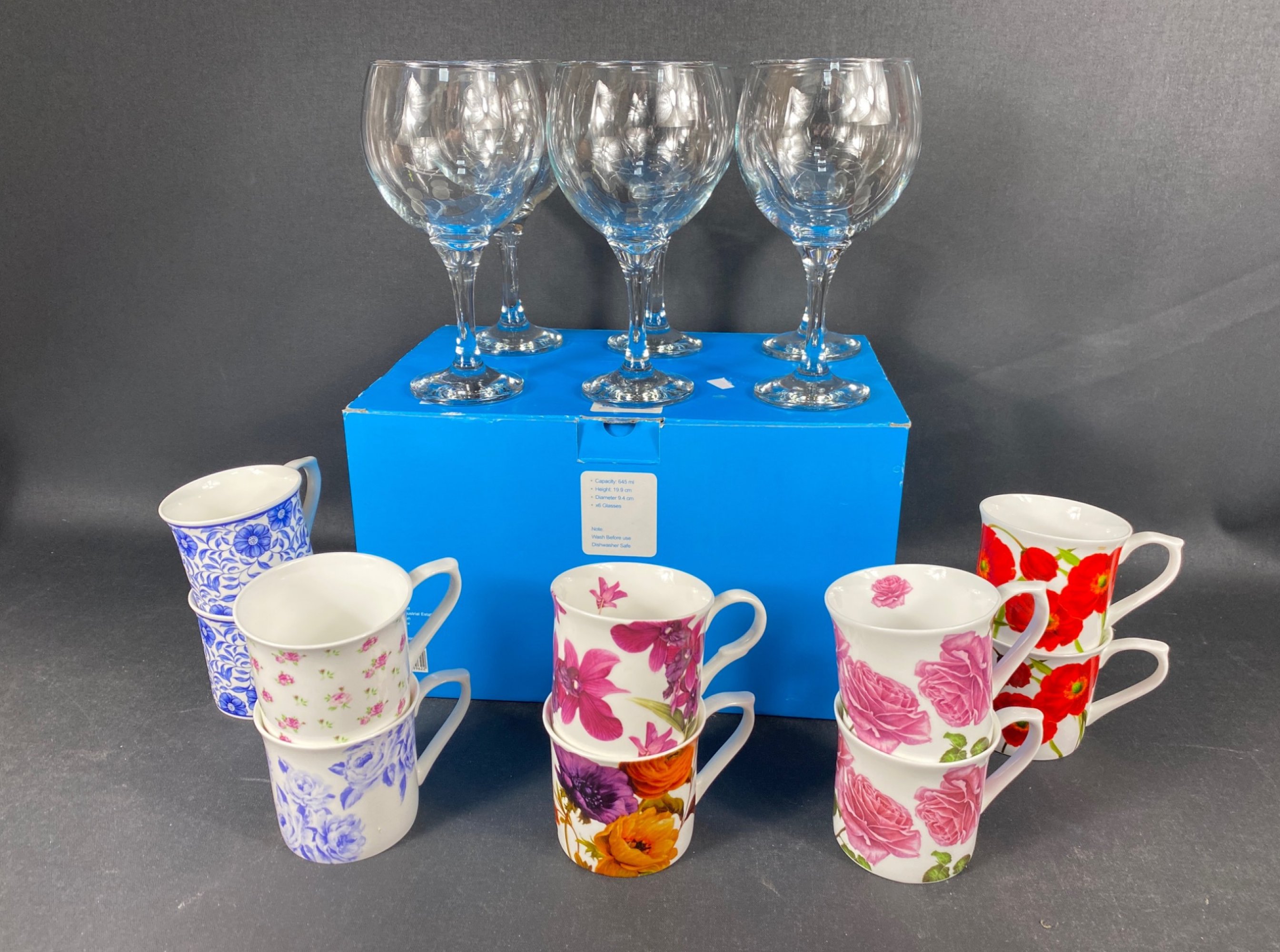 Boxed set of six large balloon Gin glasses and ten modern ceramic mugs with floral decoration.