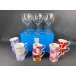 Boxed set of six large balloon Gin glasses and ten modern ceramic mugs with floral decoration.
