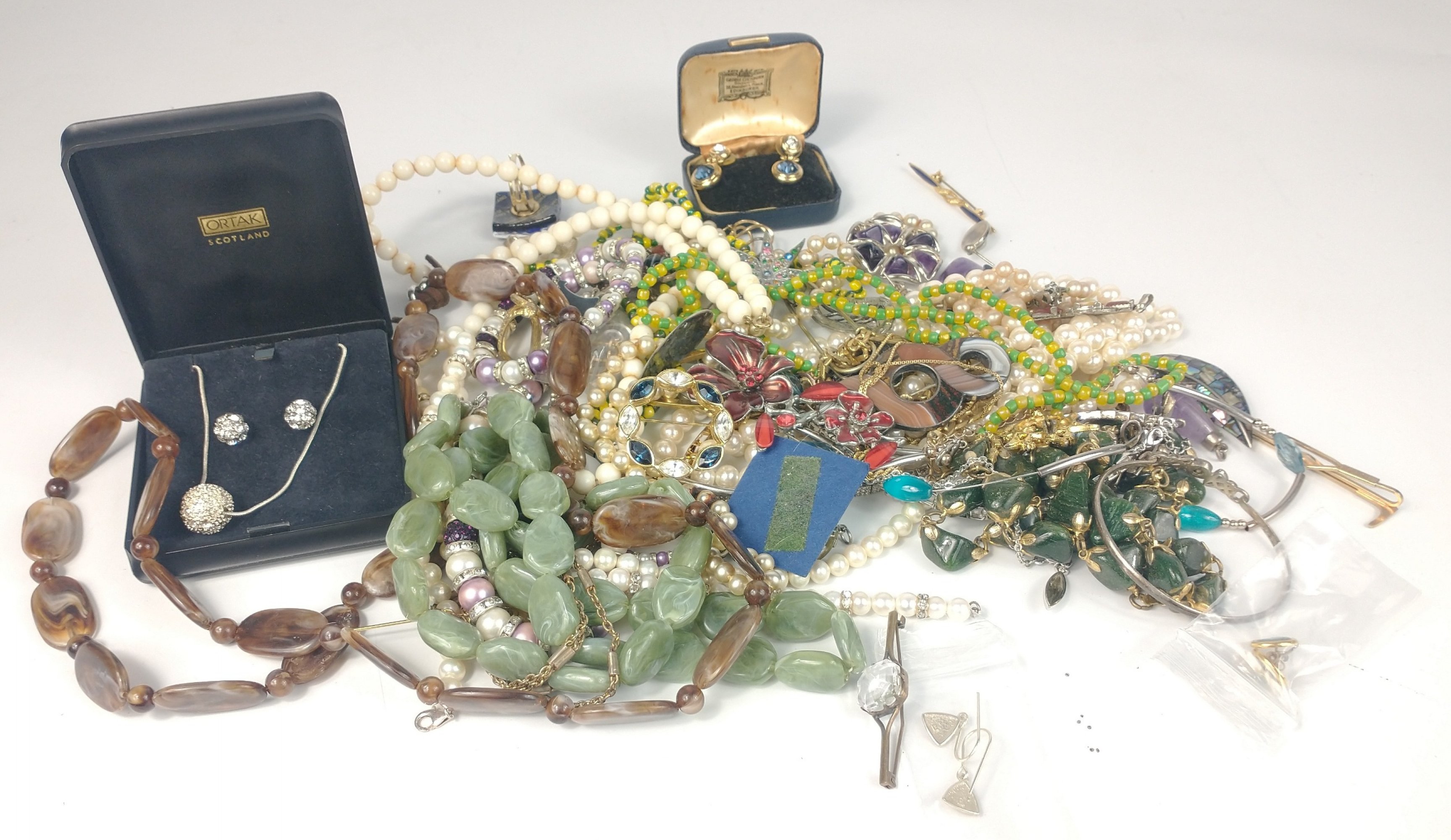 A bag of costume jewellery to include faux pearls, several brooches, strings of beads and pairs of