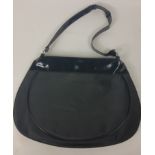 A black fabric shoulder bag with patent shoulder and strap labelled Versace Parfums, 1 zipped