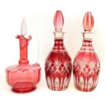 A pair of flash ruby decanters and one other cranberry decanter.