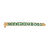 A 9ct gold emerald and diamond hinged bangle,