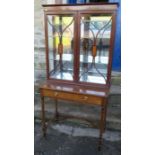 An Edwardian mahogany cabinet on stand, the upper section having two glazed doors with satinwood