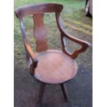 An Edwardian oak swivel office chair, with solid vase splat and saddle seat, raised on four straight