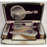 A cased hallmarked silver dressing table set, comprising a hand mirror and two pairs of brushes, all