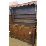 An 18th century oak and fruitwood cupboard dresser, having close boarded delft rack over cupboards