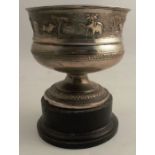 An Indian white metal pedestal bowl, decorated with a band on embossed animals in landscape,