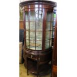 A mahogany display cabinet, of curved form, with inlaid and carved decoration, fitted with drawers