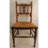 A Liberty & Co walnut Moorish style child's chair, with rush seat, and having a Mushribeyeh panel