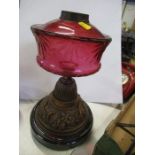 An oil lamp base, with cranberry glass oil reserve on a pressed metal base, height 14ins - glass