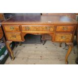 A reproduction walnut writing desk, with leather inset top and carved decoration, having an