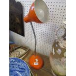 An orange metal angle poise style lamp