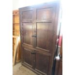 An antique stained cupboard, having two panelled doors over two further panelled doors, opening to